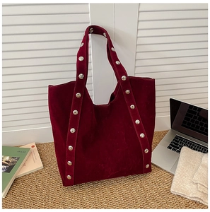 Macro shot of dark burgundy suede tote bag with stylish silver studs on long handles