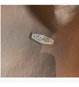Detailed close-up of the metal fashion logo emblem on a brown textured tote bag surface