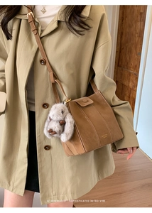 Detail of vintage brown bucket bag with plush rabbit charm and gold logo lettering