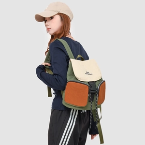 Detail view of tri-color canvas backpack with buckles shown from a side-rear angle on model
