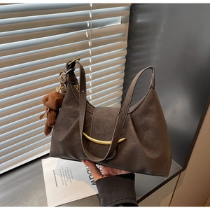 Detailed macro view of dark brown crescent bag with gold metal buckle and cute bear charm
