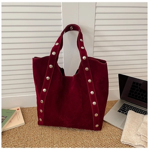 Detail of burgundy suede tote bag featuring metallic silver studs on shoulder straps