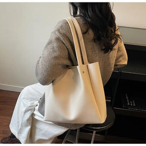 Off-white large tote bag shoulder view showing minimalist leather finish and rivets
