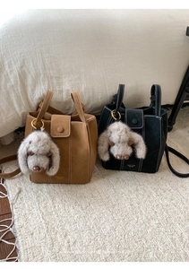 Detail of suede bucket bags in brown and black with plush rabbit charms and gold logo