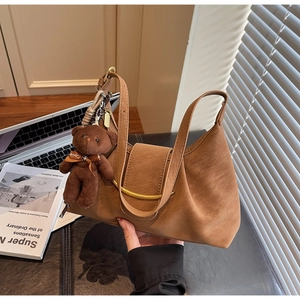 Detailed view of brown croissant bag with gold metal buckle and cute bear pendant charm