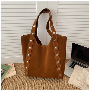 Detail of brown suede tote bag featuring silver studs with office essentials