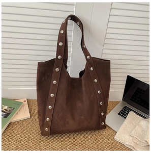 Detail of a brown suede tote bag featuring vertical silver studs for a retro industrial look
