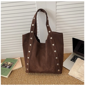 Detailed texture of dark brown suede tote bag with silver rivets on shoulder straps