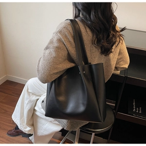 Minimalist black matte tote bag with metallic side buckle detail in lifestyle setting