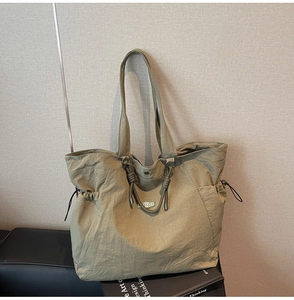 Detail view of large olive green nylon tote bag featuring drawstring side pockets