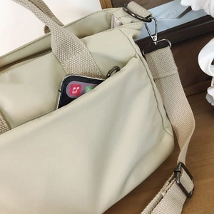 Detail of nylon shoulder bag side pocket with smartphone and metal strap hooks