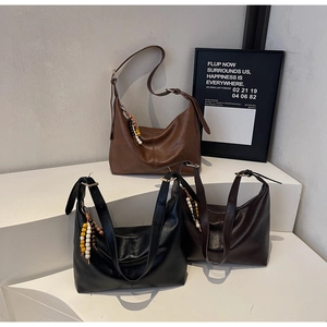 Détail de grands sacs hobo en marron, noir et café avec des breloques en perles de bois