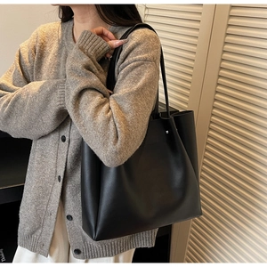 Close-up of minimalist black tote bag with slender shoulder straps and matte leather finish