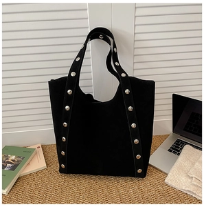 Detail of black suede tote bag with silver metal rivets on straps for office commute