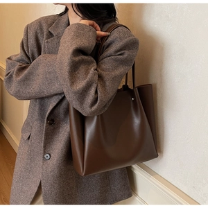 Side view of dark brown leather tote bag worn with a wool blazer for daily commute