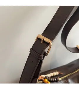 Détail du sac cabas en cuir marron avec bandoulière réglable et décorations en perles