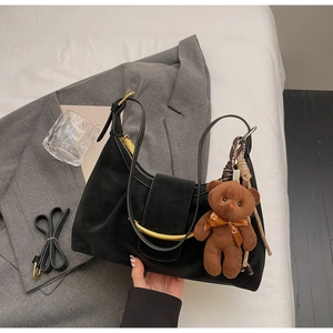 Detail of black crescent hobo bag with gold buckle and brown plush bear charm