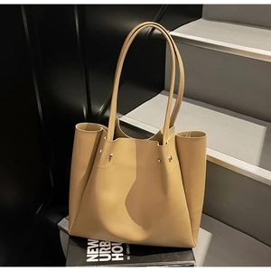 Detail view of khaki tote bag featuring side fold design and silver rivet accents