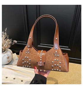Detailed close-up of brown studded underarm bag with silver rivets and buckle