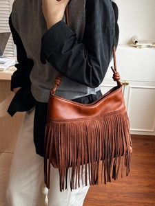 Borsa a secchiello vintage in pelle marrone con frange e tracolla su modella donna