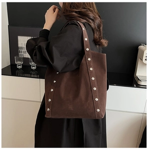Close-up of brown suede tote bag featuring metallic silver studs and premium texture