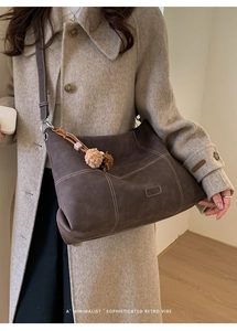 Detalle de bolso tote de ante con costuras en contraste y adornos puesto en modelo