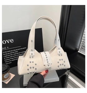 Close-up of beige leather shoulder bag with silver rivet details and retro buckle design