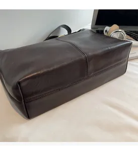 Détail d'un sac cabas en cuir marron foncé avec couture centrale et décor de bureau