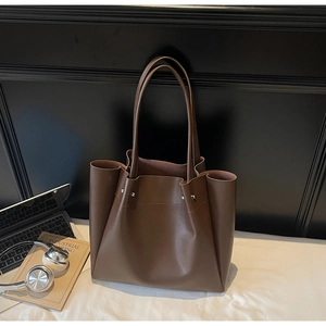 Macro detail of dark brown leather tote bag with silver studs and narrow shoulder strap