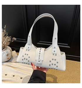 Close-up of white leather shoulder bag with silver studs and magnetic buckle closure