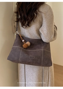 Detalle de bolso tote marrón con costuras en contraste y colgante de felpa en modelo