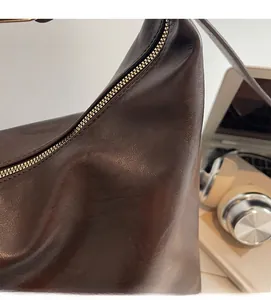 Gros plan sur un sac rétro en cuir marron avec fermeture éclair et texture souple