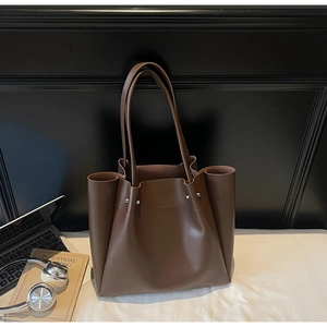 Close-up of brown PU leather tote bag with silver rivets and sleek minimalist texture