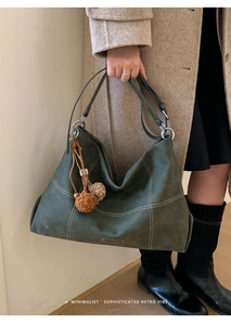 Detail view of dark green retro tote bag with white contrast stitching and plush charms