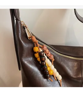 Détail d'un sac en cuir marron foncé avec des perles rétro colorées et un zip doré