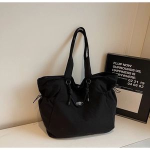 Close-up of black nylon tote bag featuring drawstring detail and silver metal hardware