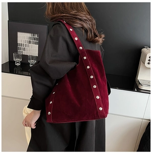 Detail of burgundy velvet tote bag with silver studs on straps and edges