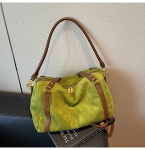 Détail du sac Boston en daim vert avec poignées en cuir marron et finitions dorées