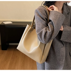 Detailed side view of a large light brown leather tote bag with wide strap on a model
