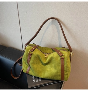 Vue détaillée du sac Boston en daim vert herbe avec anses en cuir marron et boucles dorées