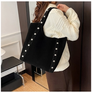 Detail view of black suede tote bag with silver rivets and elegant shoulder strap design