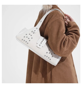 Detailed view of a white leather underarm bag with silver rivets and vintage style