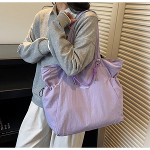 Detail of purple tote bag showing crinkle nylon fabric and decorative knot on shoulder strap