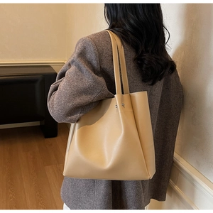 Close-up of a beige minimalist tote bag showing soft leather texture and silver rivets