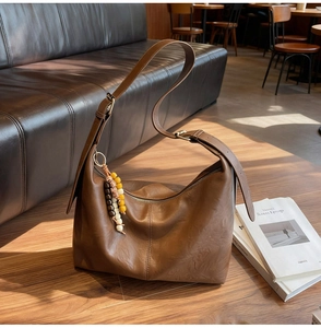 Détail du sac hobo en cuir marron avec des breloques ethniques en perles de bois