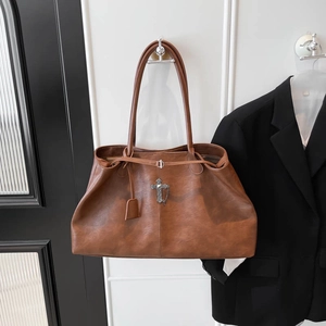 Dettaglio della borsa tote marrone vintage con pendente a croce metallica e catenina