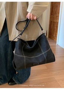 Detail of black tote bag with white contrast stitching and silver metal ring hardware