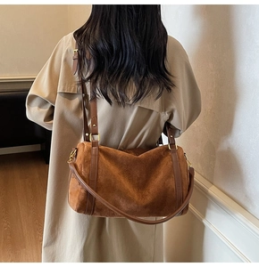 Détail du sac bandoulière en daim marron avec lanières en cuir et boucles dorées