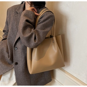 Khaki faux leather tote bag on shoulder with gray tweed blazer for office look