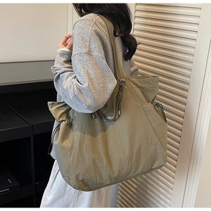 Detail view of olive green waterproof nylon tote bag with drawstring side pocket and logo